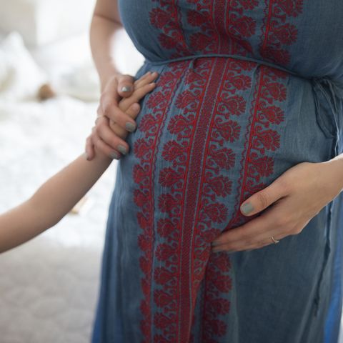 mujer poniendo a su hija a notar la primera patada de su bebé