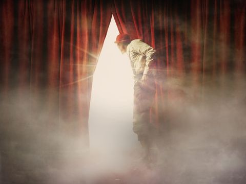 Caucasian man peering through red curtain