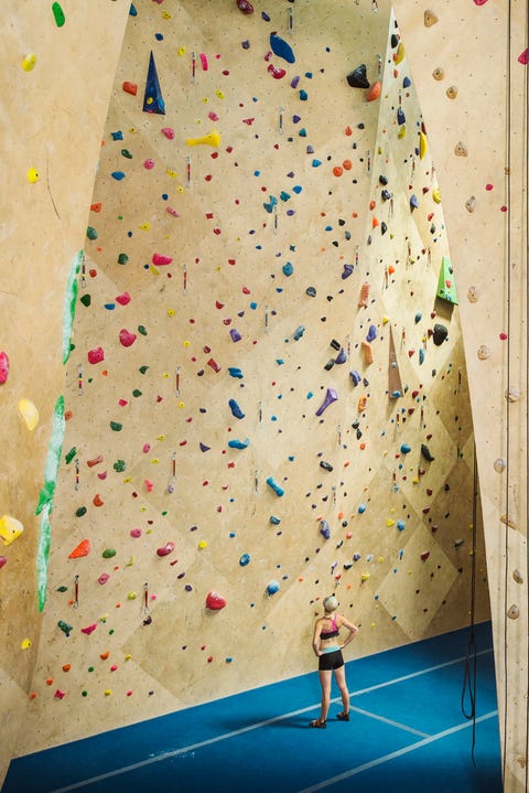 Caucasian woman examining indoor rock wall Caucasian woman examining indoor rock wall