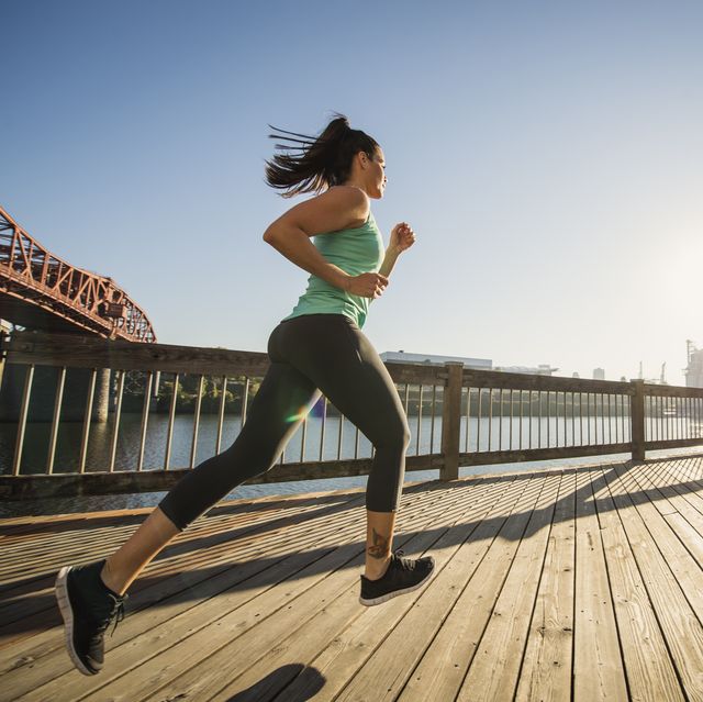 caucasian woman jogging on urban waterfront