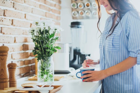 Caucasian woman stirring coffee in kitchen