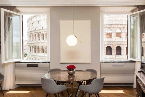 airbnb in rome met uitzicht op colloseum met vier stoelen om een eettafel en openstaande ramen