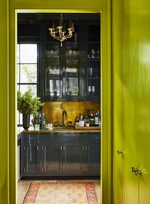 dark glossy cabinets in a bar with brass hardware and countertops and backsplash