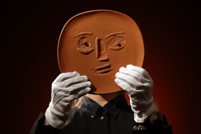 london, england   february 17 a member of staff poses with an unglazed terracotta plate entitled visage aux grands yeux by pablo picasso at christies auction house on february 17, 2016 in london, england forming part of the queen annes gate works from the art collection of sting and trudie styler auction on february 24, it is expected to fetch between 1,200 1,800 gbp photo by carl courtgetty images