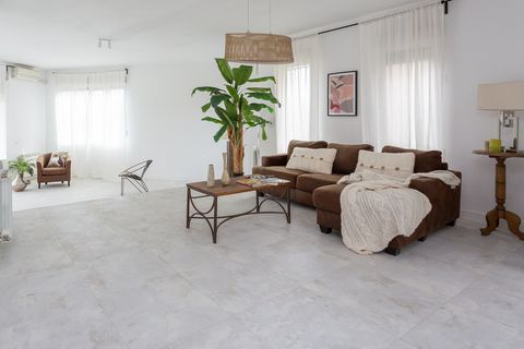 salón con sofá con chaise longue marrón y palmera
