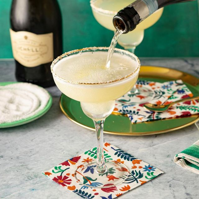 champagne cocktails pouring champagne in margarita glass with green plate salt and floral napkins behind