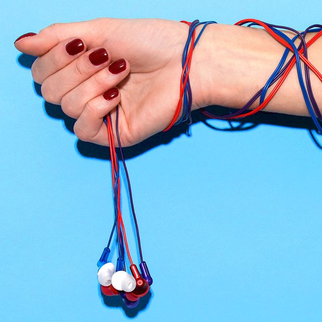 woman with red nail polish holding three colorful cheap earbuds