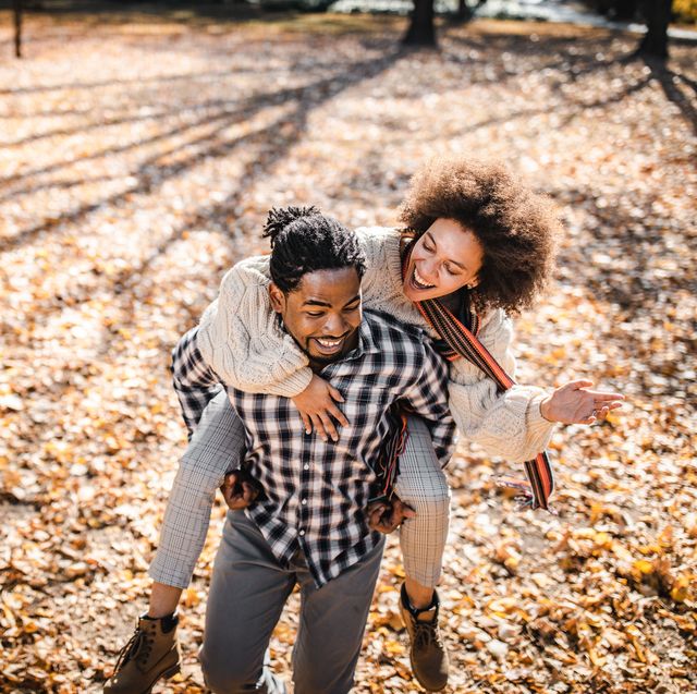 cheerful african american couple piggybacking in autumn at the park