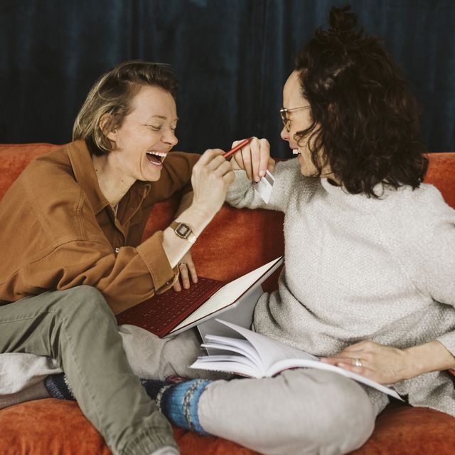 cheerful lesbian couple sitting together on sofa at home