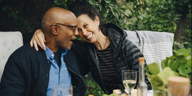 cheerful senior man and woman enjoying while sitting at dinning table during garden party