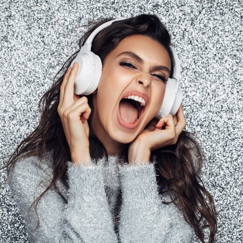 Cheerful young woman listening to the music new years colors silver