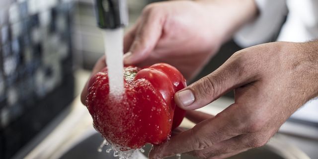 chef washing pepper red pepper under tap, close up