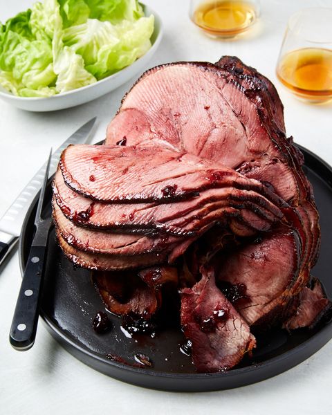 cherry bourbon glazed ham spiral cut on a black plate next to a steak knife