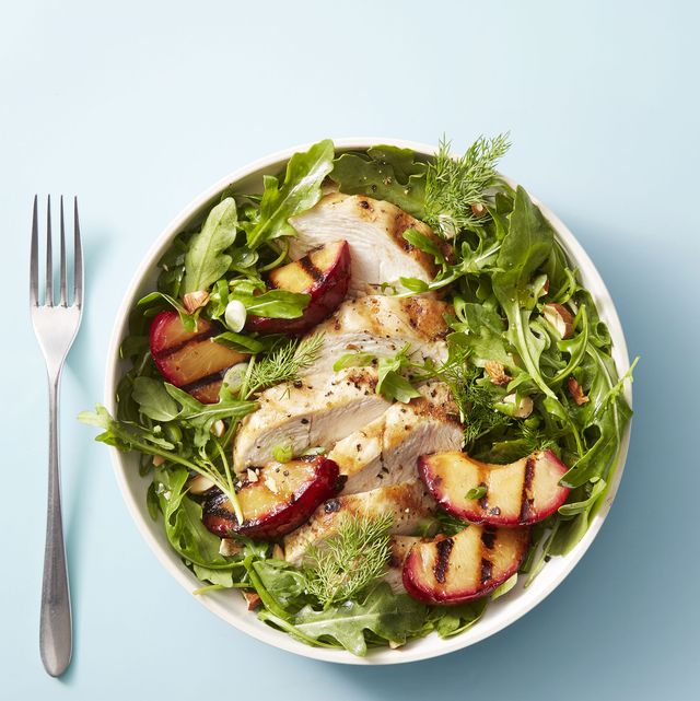 chicken and red plum salad with mixed greens and served in a white bowl
