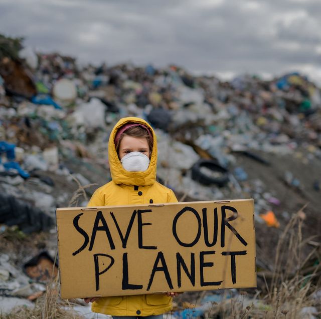 front view of small child holding placard poster on landfill, environmental pollution concept