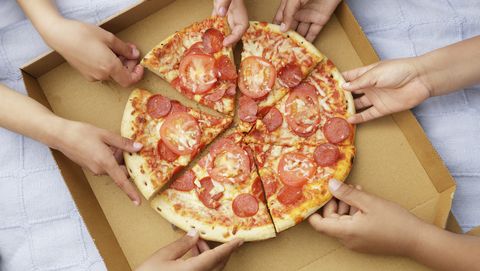 Children's hands taking pizza slices out or box