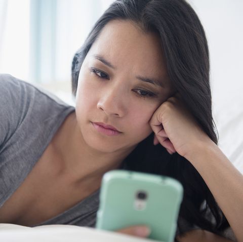 Woman staring at cell phone on bed- slow fade