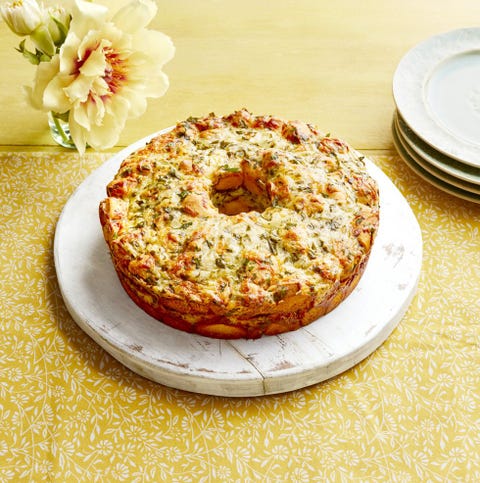cheesy monkey bread on white circle board with yellow background
