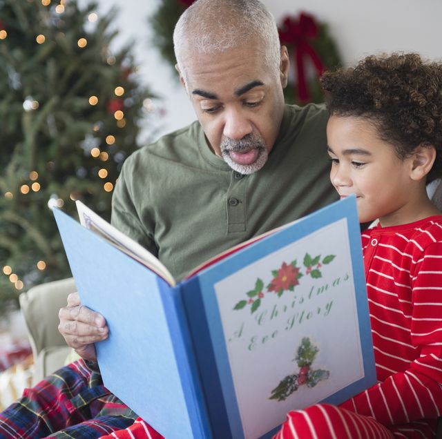 mixed race grandfather reading to grandson at christmas