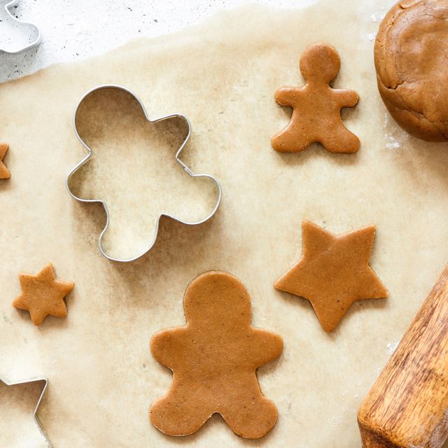gingerbread and star cookie cutters on parchment paper with rolling pin and gingerbread cookie dough