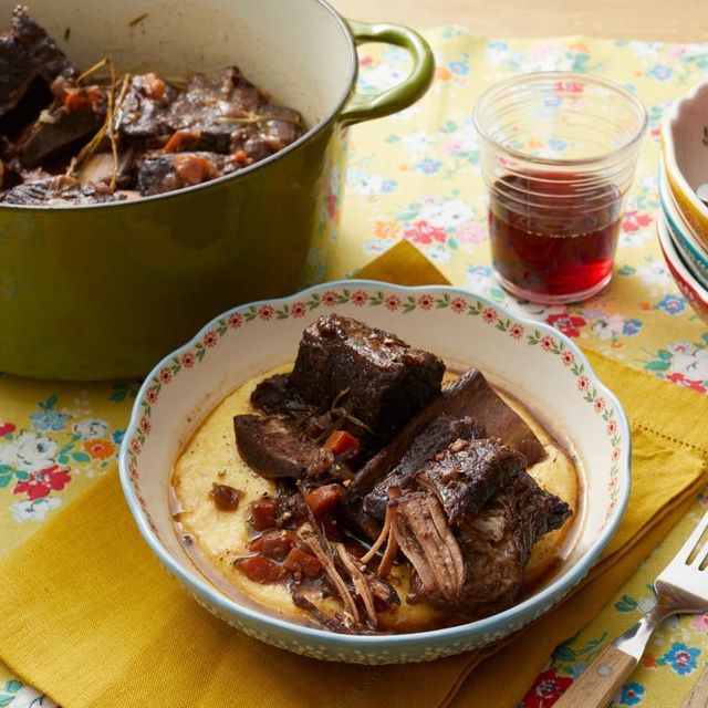 short ribs and polenta in bowl with dutch oven and glass of wine