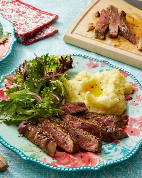 pan fried rib eye with mashed potatoes and salad on floral plate