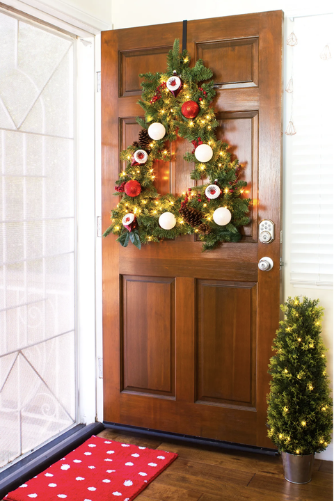 christmas door decorations, tree shaped wreath with ornaments and lights hanging on the front door
