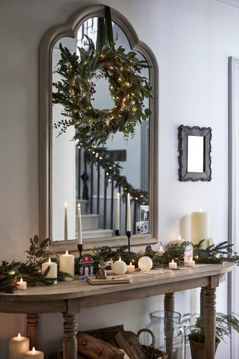 christmas hallway decorations with wreath above the mirror and candles on console table