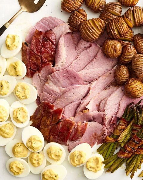 honey mustard glazed ham sliced on board with eggs, potatoes, and asparagus