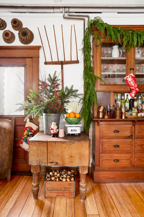 an antique butcher block table sits beside a wooden cabinet made into a bar in a farmhouse kitchen in new york