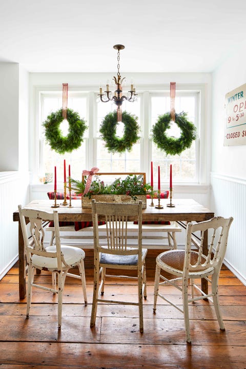 a wooden table set in a nook with a bench and three chippy chairs