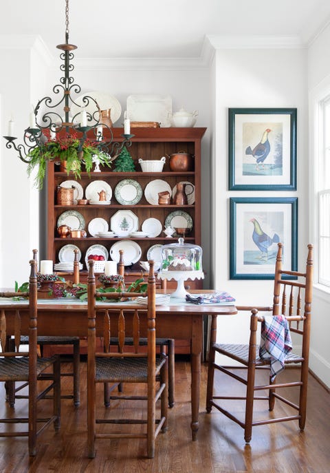 a wooden kitchen table and chairs with a china cabinet behind that is filled with copper collectibles and christmas dishware