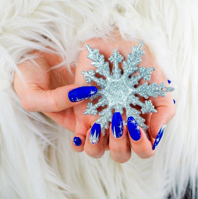 christmas nail ideas  woman's hands painted blue and holding a glittery snowflake