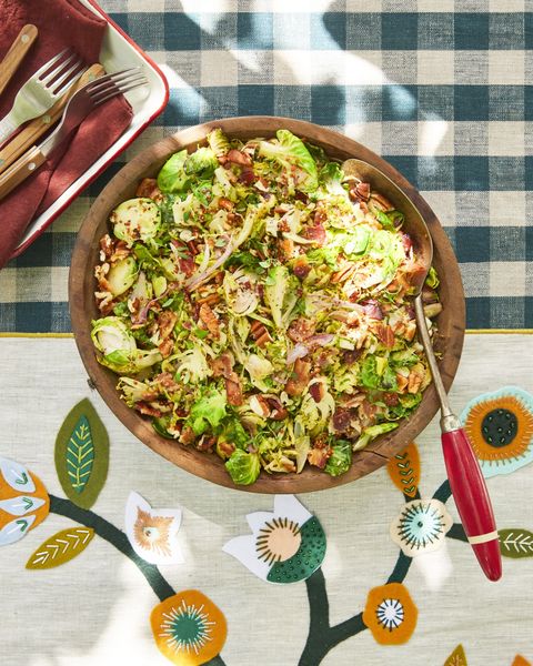 shaved brussels sprouts with bacon and warm apple cider dressing in a wooden bowl with a serving spoon
