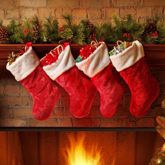 christmas stockings hanging from a mantelpiece above glowing fireplace