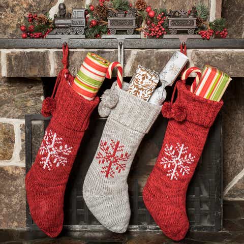 red and gray stockings with presents inside hung by a brick fireplace