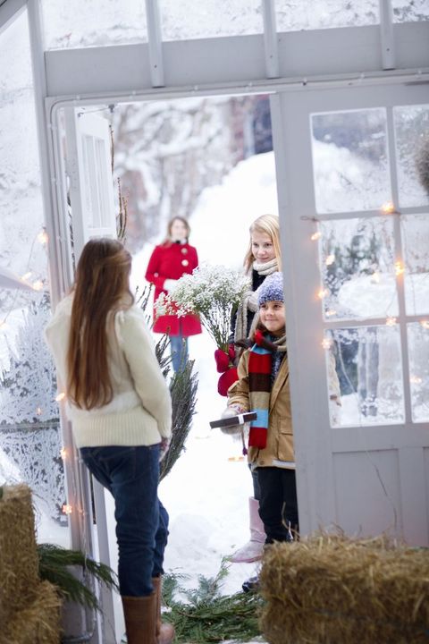 woman answering door to children holding gifts