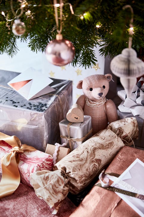 close up of presents underneath a christmas tree a small teddybear and silver and gold wrapped presentsprecious presentsgive giftwrapping a touchof glamour by usingpapers in silver, copperandmarbled finishes