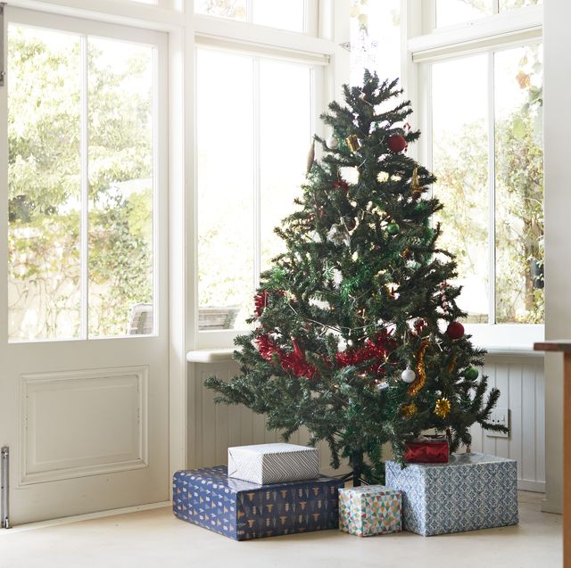 christmas tree with gift boxes by window at home