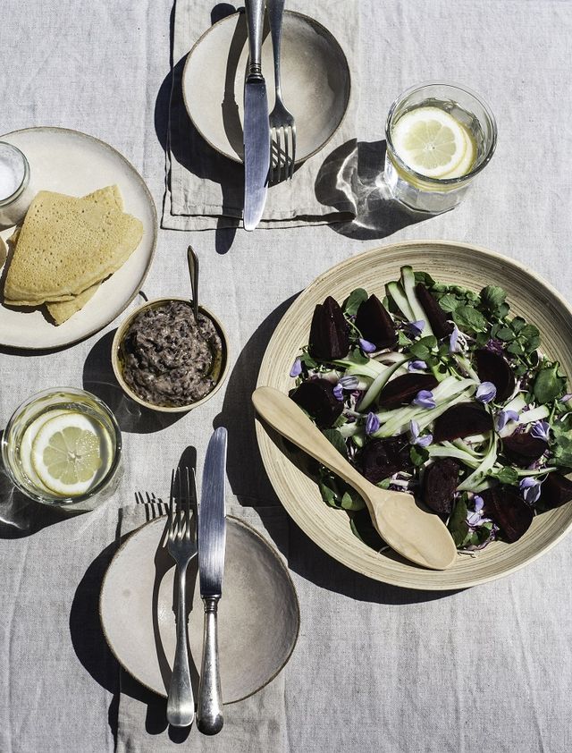 a fresh and colourful spring salad of beetroot, cucumber, cress, arugula and garnished with wisteria flowers freshly picked a sunny day, healthy food and a pretty table set for two in this glamorous picnic scene
