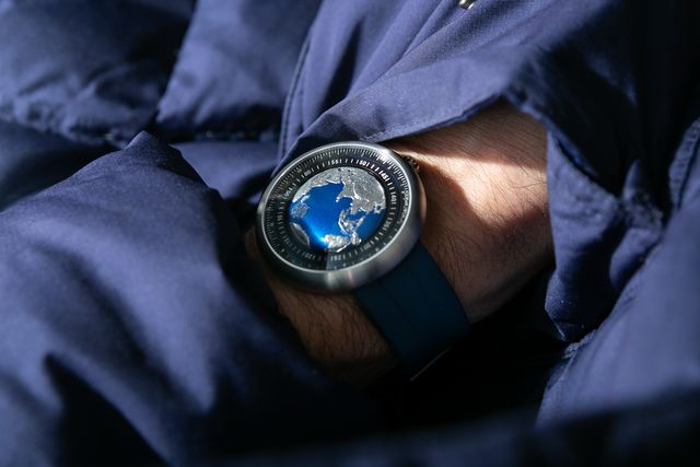 man wearing a ciga design blue planet watch on his wrist with his hand in a pocket