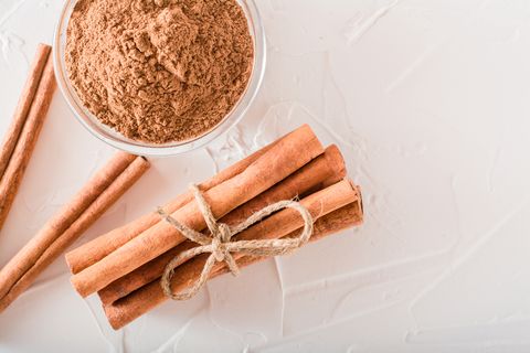 Cinnamon sticks, tied with a rope, and ground cinnamon in a bowl lie on the table
