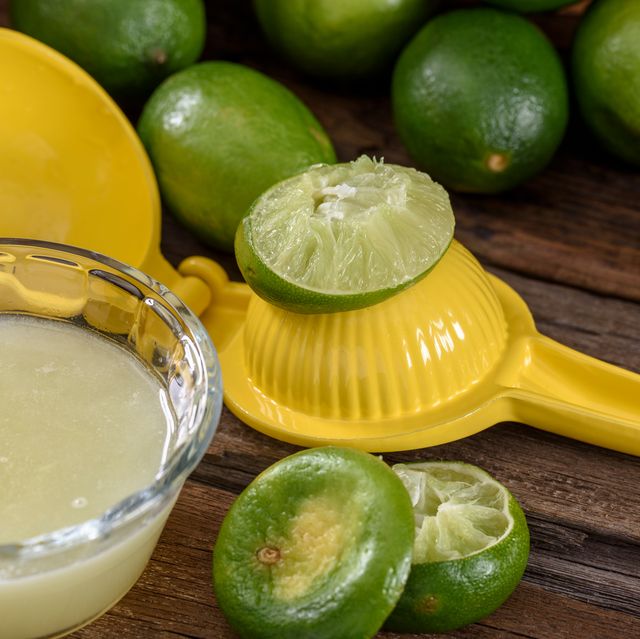 yellow citrus juicer with limes and juice