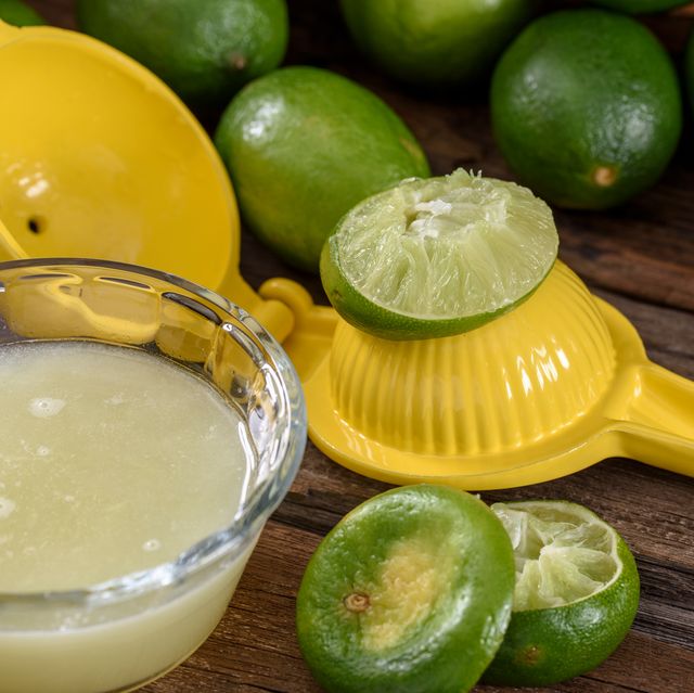 yellow citrus juicer with limes and juice