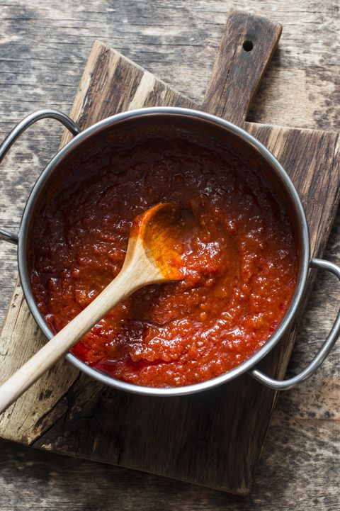 classic homemade tomato sauce in the pan on a wooden chopping board on brown background, top view pasta, pizza tomato sauce vegetarian food