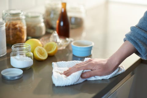 woman cleaning a kitchen worktop with natural cleaning products