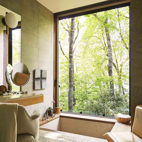 bathroom with sunken tub and window overlooking wooded area