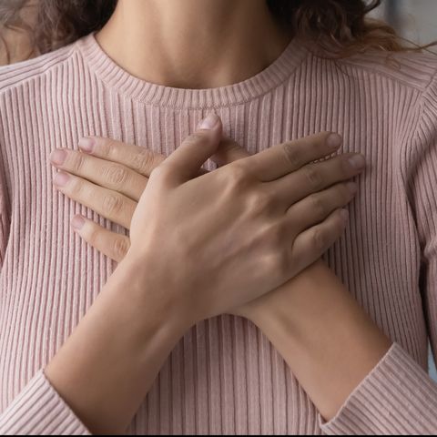 close up happy sincere female holding folded hands on chest