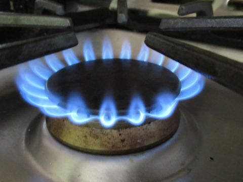 close up natural gas stove burner with blue flame