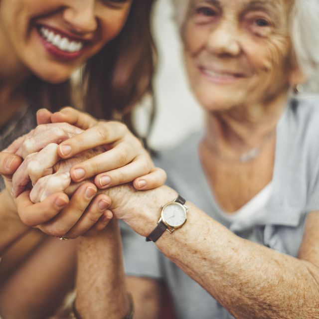 close up of a smiling nurse holding a senior woman's hand